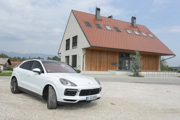 Slovenia ljubljana, 31 August 2019 - White Porsche Cayenne Coupe Turbo S from Stuttgart during test drive in front of wooden house — Stock Photo, Image