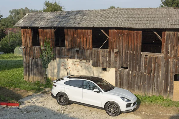 Eslovenia Liubliana, 31 de agosto de 2019 - Porsche Cayenne Coupe Turbo S desde Stuttgart durante la prueba de conducción todoterreno SUV en terreno con antigua casa de madera — Foto de Stock