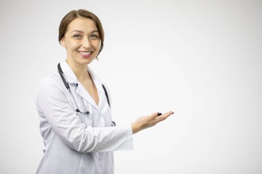Heyecanlı güzel bayan doktor beyaz arkaplandaki boş metne işaret ediyor