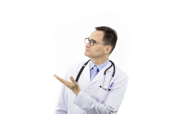 Médico de idade sênior grave em uniforme médico apontando para espaço de texto vazio — Fotografia de Stock