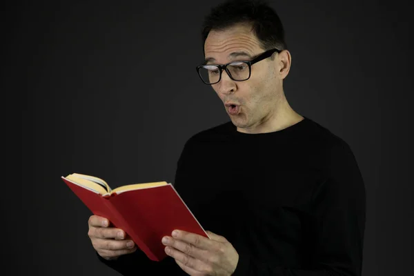 Удивленный человек в очках, читающий приключенческую книгу, интересные факты — стоковое фото