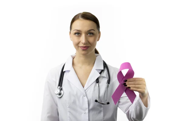 Glimlachende verpleegster in witte jas en stethoscoop houdt roze lint, symbool van oktober — Stockfoto