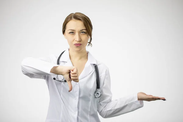 Όμορφη δυσαρεστημένος γιατρός με ιατρική στολή δείχνει απέχθεια κρατώντας ανοιχτή παλάμη — Φωτογραφία Αρχείου