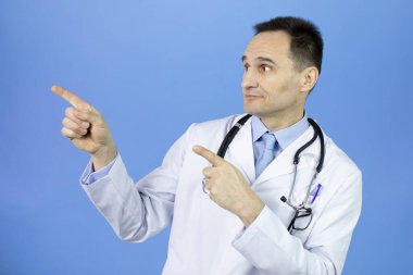 Heyecanlı doktor mavi arkaplandaki boş metin alanını işaret ediyor