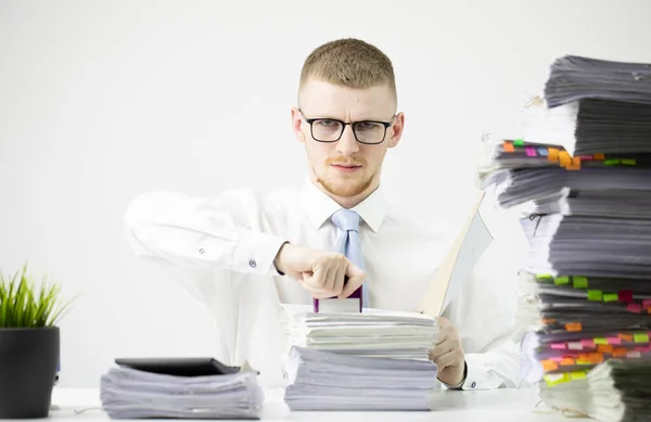 Jeune comptable sérieux travaillant au bureau au milieu de piles de paperasserie de routine — Photo