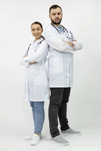 Zwei Ärzte beiderlei Geschlechts stehen Rücken an Rücken und blicken in die Kamera — Stockfoto