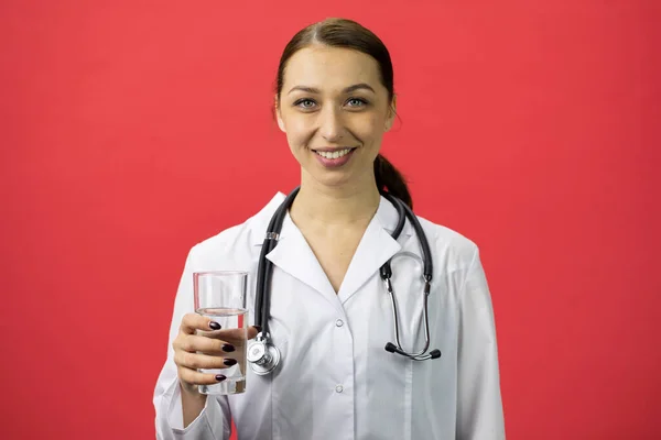 하얀 가운을 입고 있는 섹시 한 의사는 깨끗 한 식수를 들고 미소를 짓는다 — 스톡 사진