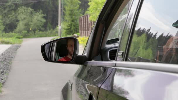 O motorista masculino ajustou o espelho lateral, apertou o cinto de segurança e começou a mover o carro — Vídeo de Stock