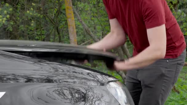 Le conducteur soulève le capot de la voiture et élimine la panne du moteur de la voiture — Video