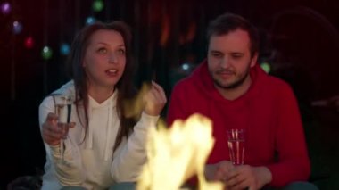 Mutlu çift, yaz gecelerinde şarap kadehleriyle ateşin başında dinleniyor.