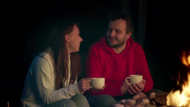 Roztomilý tisíciletý pár flirtování při pití čaje ohněm na terase v noci — Stock video