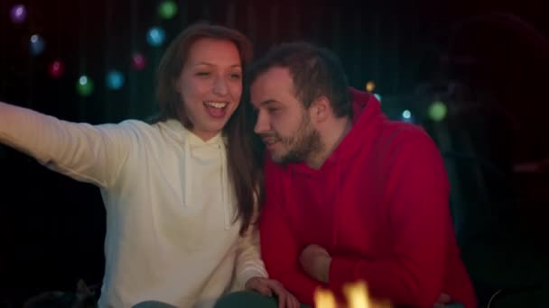 Joyeux couple mignon faire un appel vidéo avec des amis parler avec la famille près de feu de camp — Video