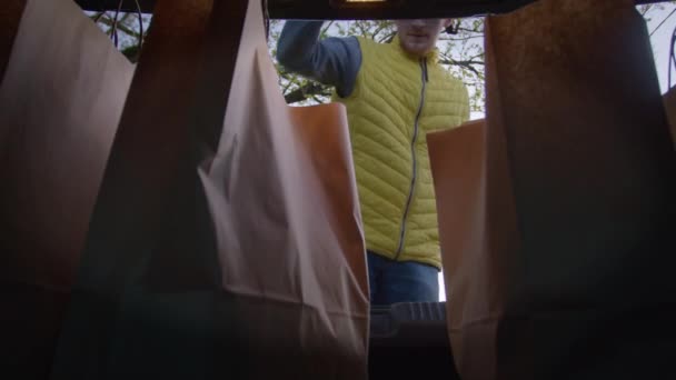 Grocery delivery man takes out friendly paper bags with groceries from the trunk — Stock Video