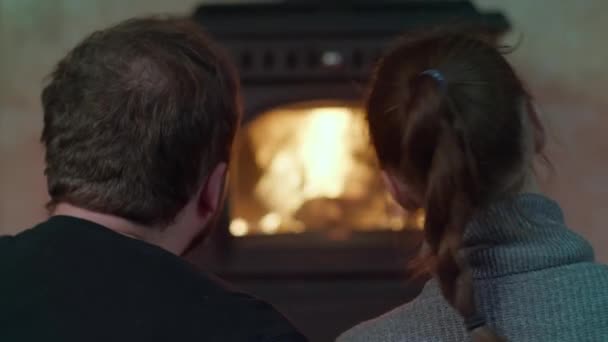 Mladý milující pár v venkovském domě sedí v blízkosti krbu objímání zpět pohled — Stock video
