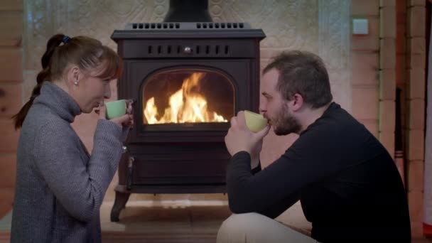 Schönes Paar hat Spaß beim Ausruhen am Kamin, trinkt heiße Schokolade — Stockvideo