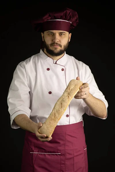 Knappe bebaarde chef-kok in uniform houdt baguette, brood van Frans brood — Stockfoto