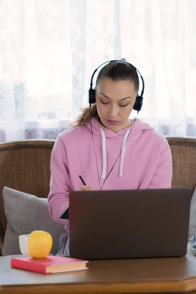 Linda chica morena en los auriculares funciona de forma remota con el ordenador portátil — Foto de Stock