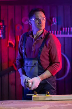 Koruyucu gözlüklü ve eldivenli adam garajda metal işçiliği kesecek.