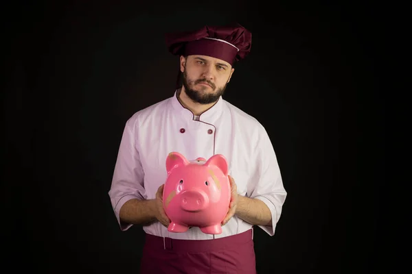Droevige chef-kok in uniform houdt gebroken roze spaarvarken bank met pleister crisis — Stockfoto