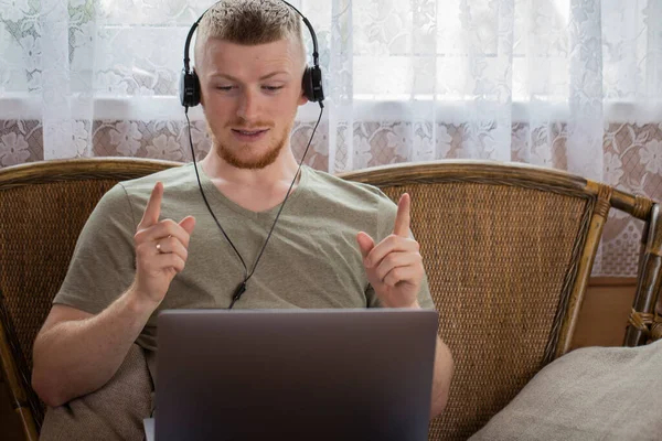 Hombre en auriculares gesticulantes se comunica en redes sociales en casa de campo — Foto de Stock