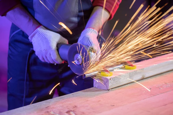 Nahaufnahme eines von Hand geschliffenen Metallrohres mit Funken in farbigem Licht — Stockfoto