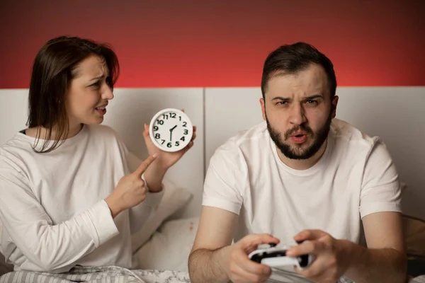 Homme avec des joysticks jouer à des jeux vidéo dans le lit la nuit ignorant sa femme — Photo