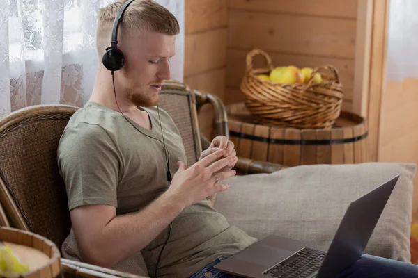 young man in headphones works with laptop and communicates in social networks
