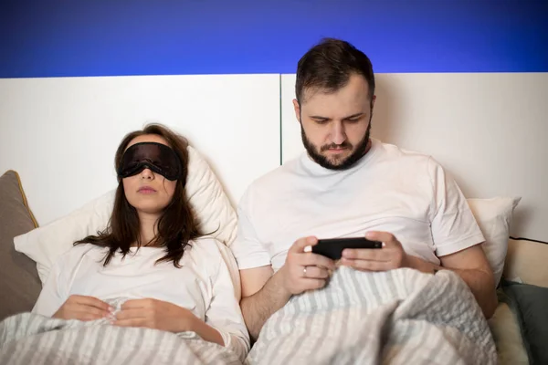 男はベッドの上でビデオゲームをプレイしながら、女性はマスクで寝ている — ストック写真