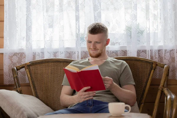 Kırsal kesimdeki bankta kitap okuyan neşeli genç adam. — Stok fotoğraf