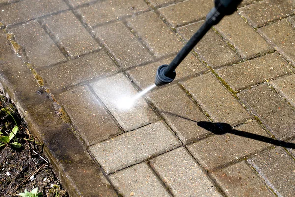 high-pressure washer watering concrete stones of garden line in country house