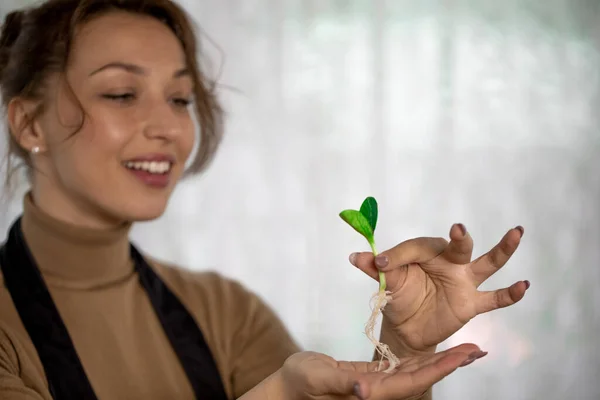 Alegre chica atractiva con sonrisa sosteniendo brote de flor antes de plantar en interiores — Foto de Stock