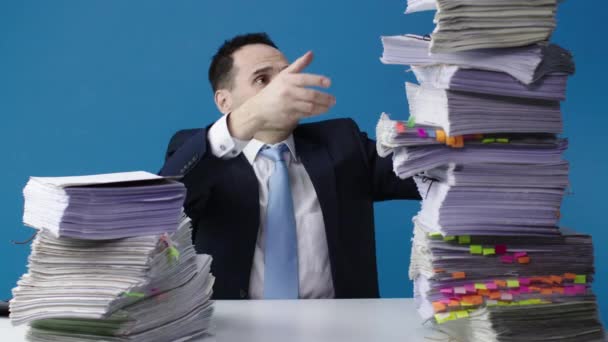 Стрессовый бухгалтер-менеджер берет стопку незавершенных документов из большой кучи — стоковое видео