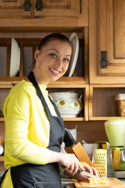 Siyah önlüklü genç güzel manken rahat ahşap bir kır evinin mutfağında poz veriyor.