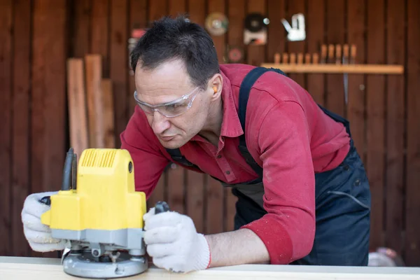 Carpenter works on wood beam with milling tool close up at cottage workshop — Stock Photo, Image