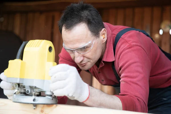 Artigiano che lavora su pezzo in legno con fresatrice da vicino in officina — Foto Stock