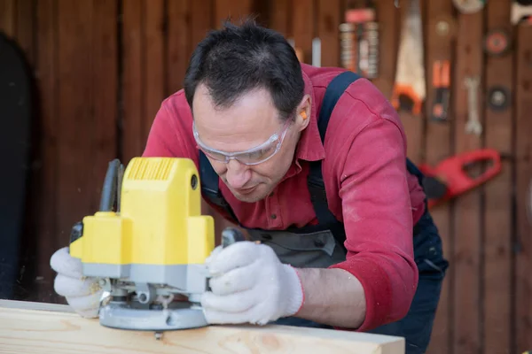 40s uomo elabora dettaglio in legno con friggitrice a laboratorio casa di campagna — Foto Stock