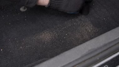 Erkek temizleyici arabanın zeminini kumun içinden süpürüyor..