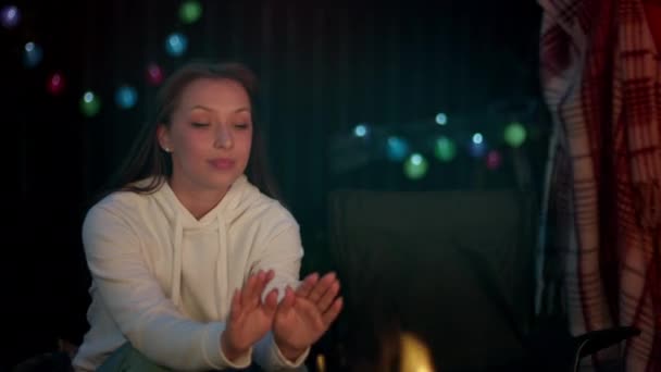 소녀는 불옆에 앉아 손을 덥히고 있다. 남성은 치태로 소녀를 덮는다 — 비디오
