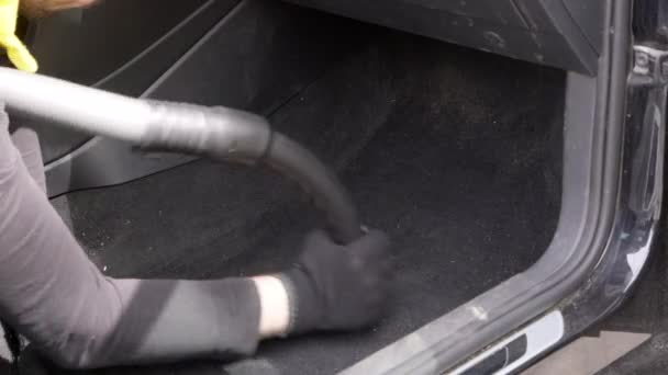Travailleur masculin aspirant un intérieur de voiture sale avec un aspirateur.