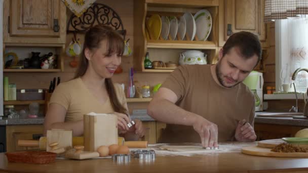 Een man en een vrouw sneden figuren voor koekjes in een deeg. — Stockvideo