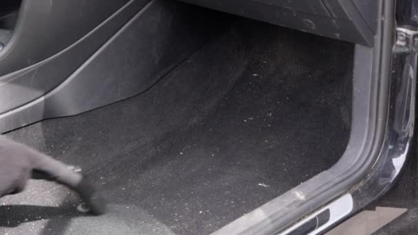Caucasian male worker removes accumulated dust and dirt in car with a vacuum cleaner. — Stock Video