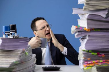 Yorgun ofis çalışanı koca bir yığın belgeyle masada oturmaktan yoruldu.
