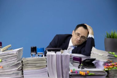 Çok çalışan işadamı ofis masasında uyuyakalmış bir sürü evrak işi var.