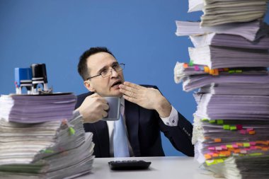 Yorgun ofis çalışanı, koca bir yığın belgeye bakmaktan yoruldu.