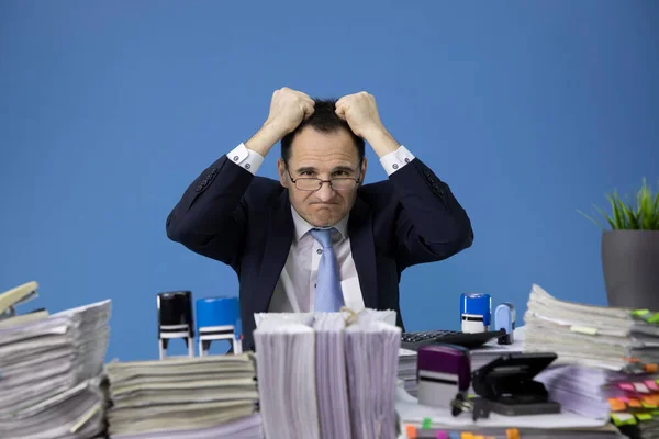 Overwerkte zakenman scheurt haar gestrest op kantoor bureau geladen met papierwerk — Stockfoto