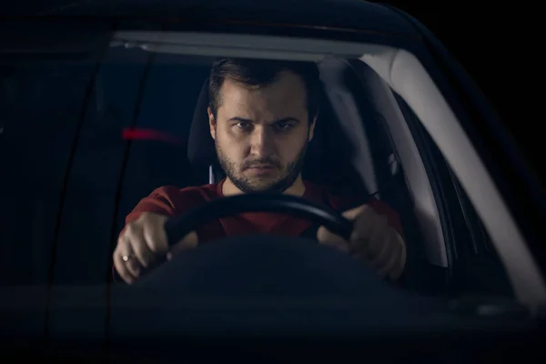 Conductor masculino seguro se sienta en el coche por la noche centrado mirando hacia el futuro — Foto de Stock