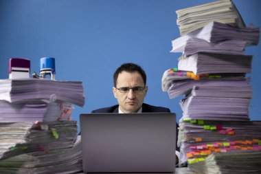 Hüzünlü iş adamı aşırı yükleme ve yorgunluk kavramında dizüstü bilgisayarla çalışıyor