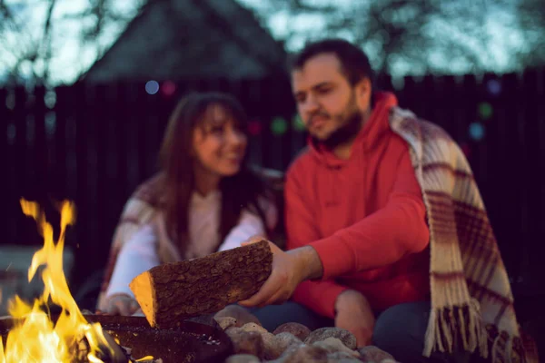 Şenlik ateşiyle romantik bir partide iki aşık, genç adam ateşe odun ekliyor.