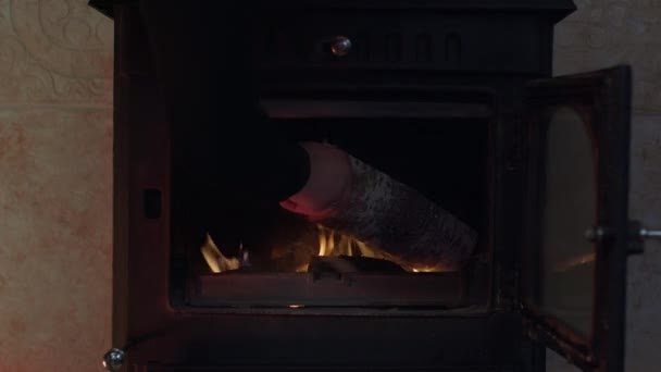 Крупный план камин в помещении пламя, рука кладет дрова в огонь в загородном доме — стоковое видео