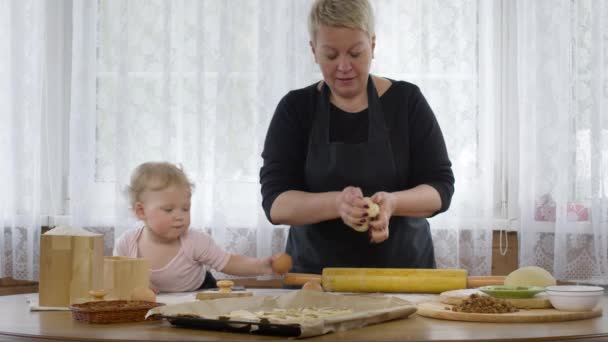 Petite petite-fille mignonne aide mamie cuire la pâte pour la pâtisserie. Intérieur confortable — Video